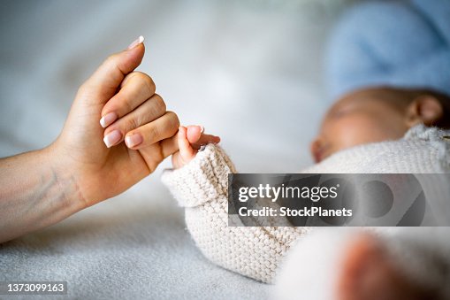 A parent holding their newborn's hand