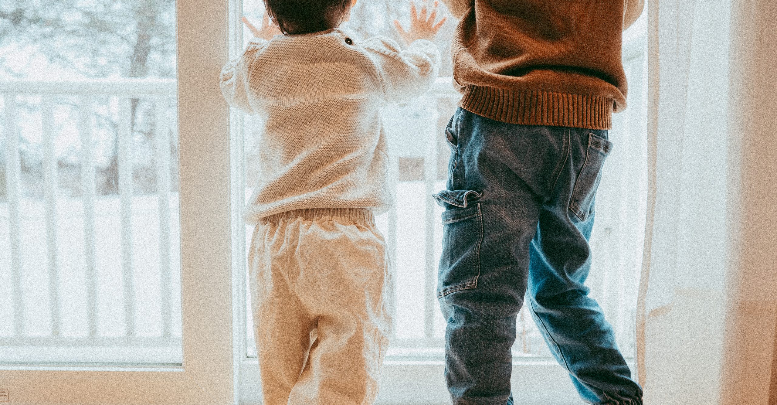 Two young children standing at a window, hands pressed to the glass — pediatric genetic testing access for every family