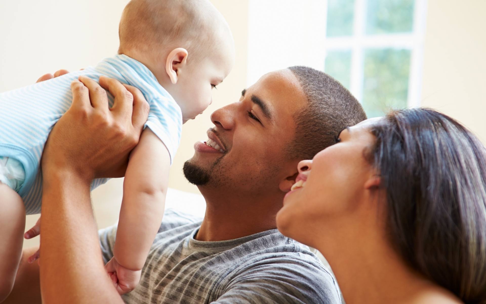 Mom and dad lift and smile at their baby